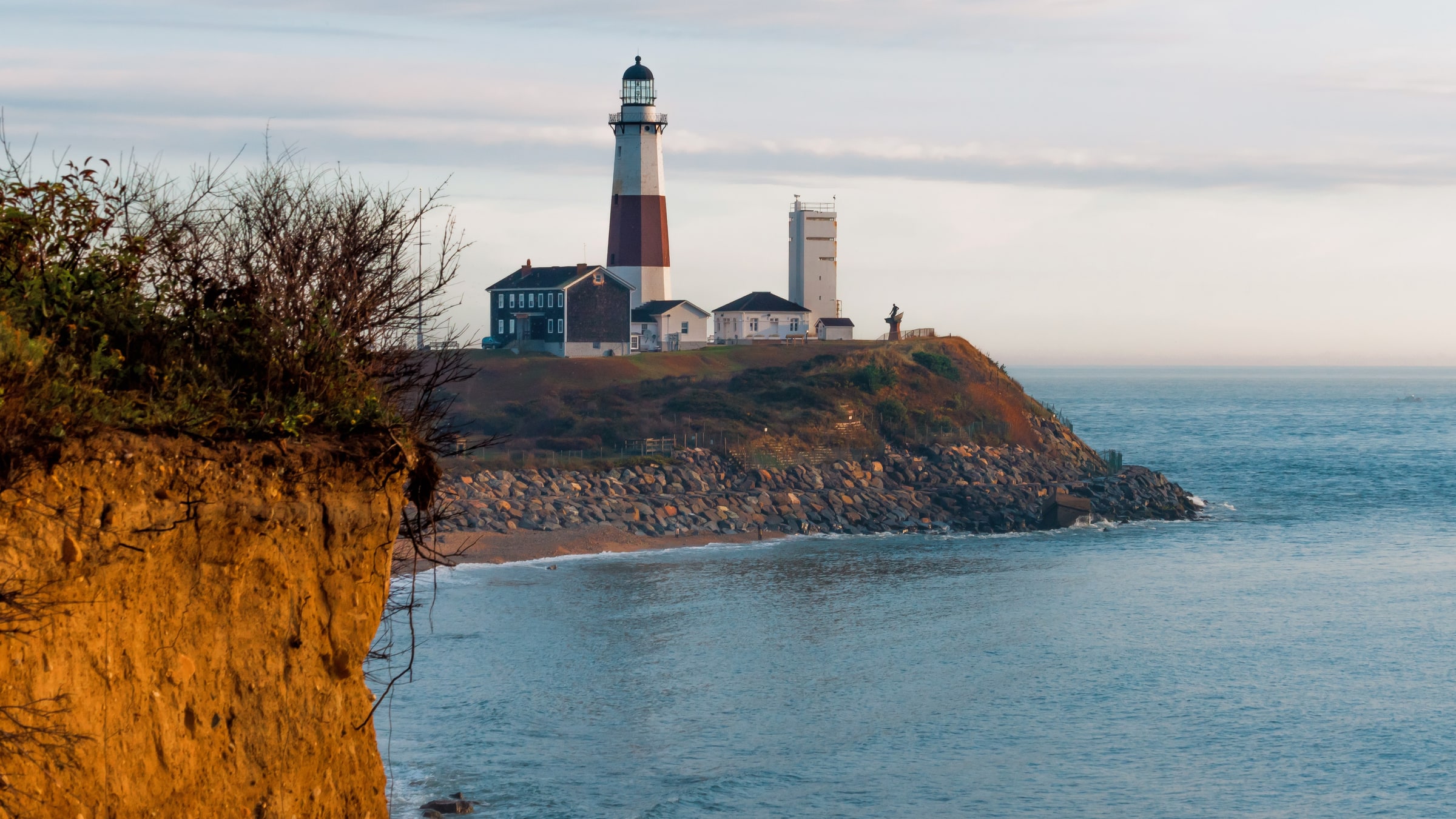 Lighthouse on a rocky headland above the water in warm evening light