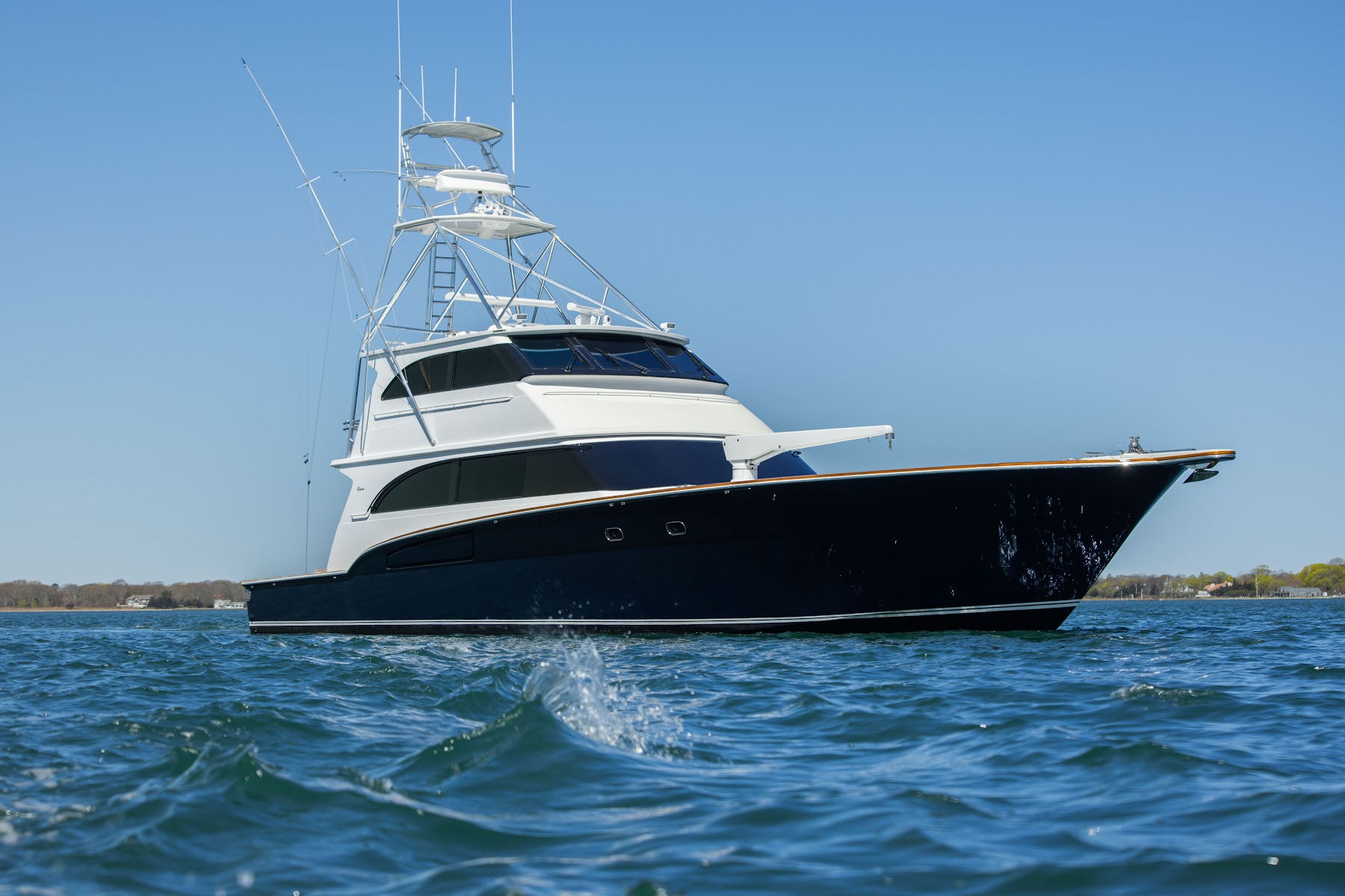 Marine photography of a dark-hulled yacht on the water beneath a clear blue sky